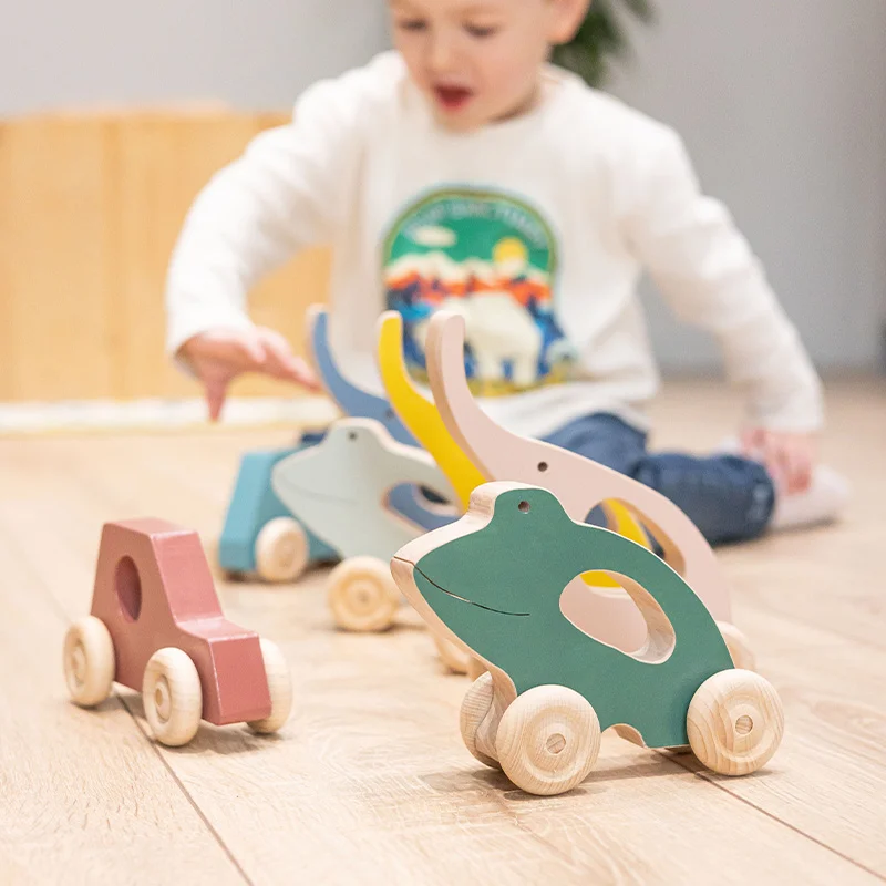 enfant entouré de jeux d'éveil en bois à roulettes