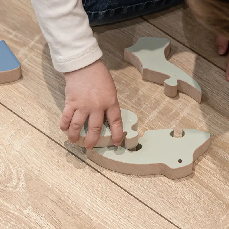 enfant imbriquant deux pièces d'un puzzle en bois grenouille