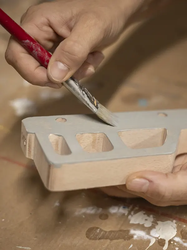 virginie en train de peindre la petite voiture en bois dans son atelier