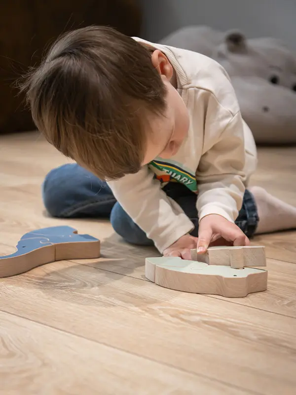 petit garçon en train d'assembler les pièces d'un puzzle en bois artisanal