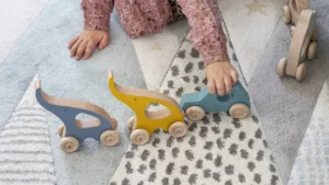 main d'enfant faisant rouler des jouets en bois pour travailler sa motricité