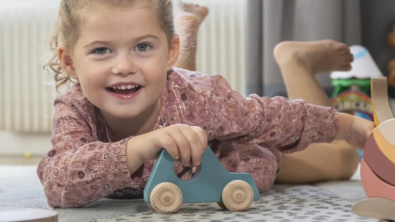 petite fille jouant avec une voiture en bois à roulettes