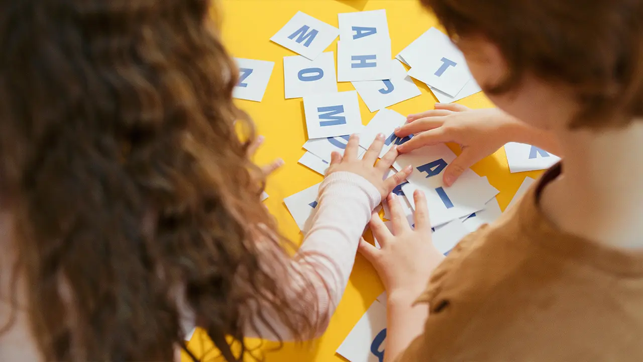 deux enfants jouent avec des lettres mobiles pour apprendre à écrire