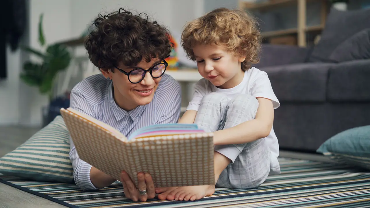 une maman et son fils en train de lire un livre au sol